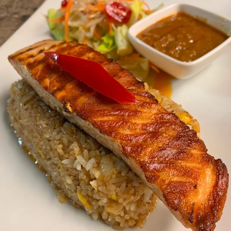 Grilled salmon on fried rice with a side salad and dipping sauce at Lotus Thai Cuisine.